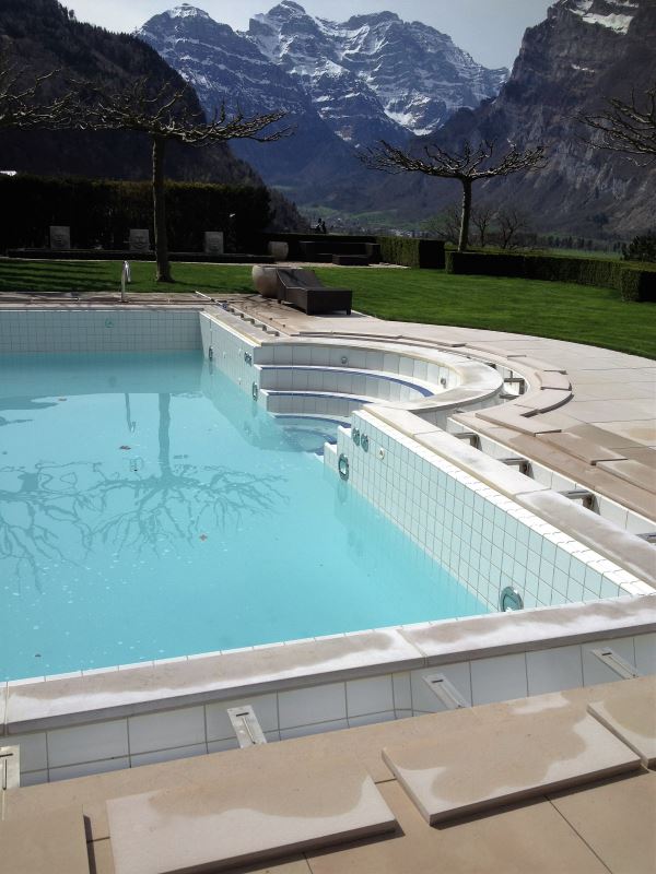 Poolbau mit Bergen im Hintergrund Natursteinumrandung